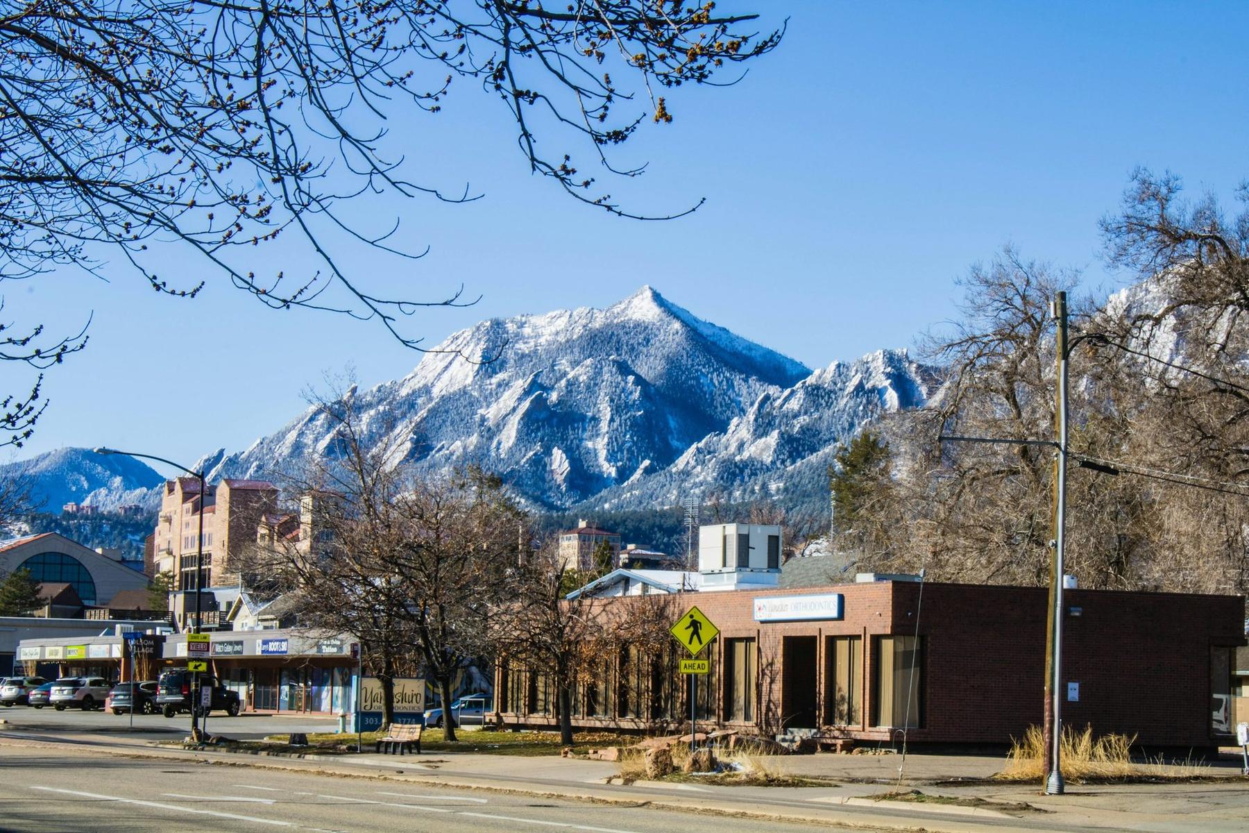 A Boulder street with snowy mountains rising beyond it.