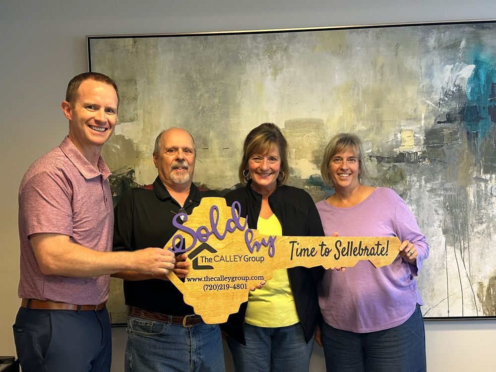 Steve Calley with three clients holding the Sold by The Calley Group key sign.