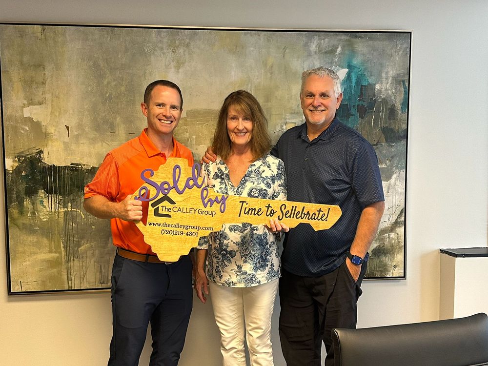 Steve Calley with a husband and wife holding the Time to Sellebrate sign at their closing.