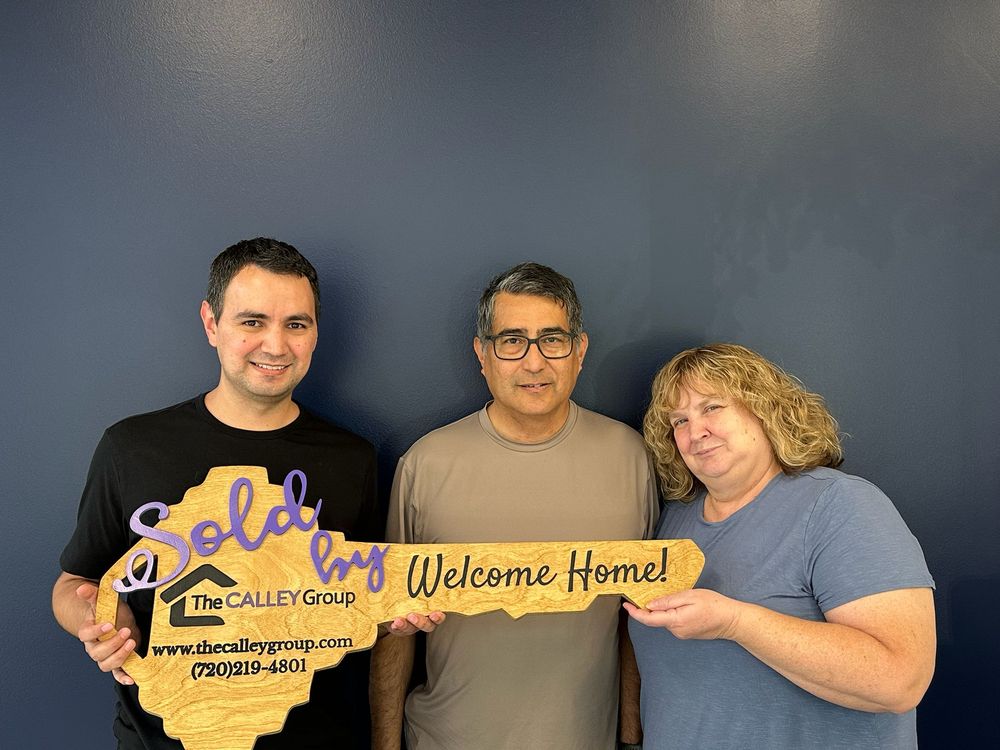 New homeowners holding Steve Calley's Welcome Home key sign on closing day.