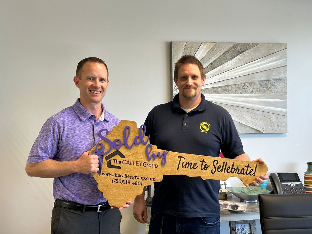 Steve Calley with a client holding the Time to Sellebrate key sign in an office.