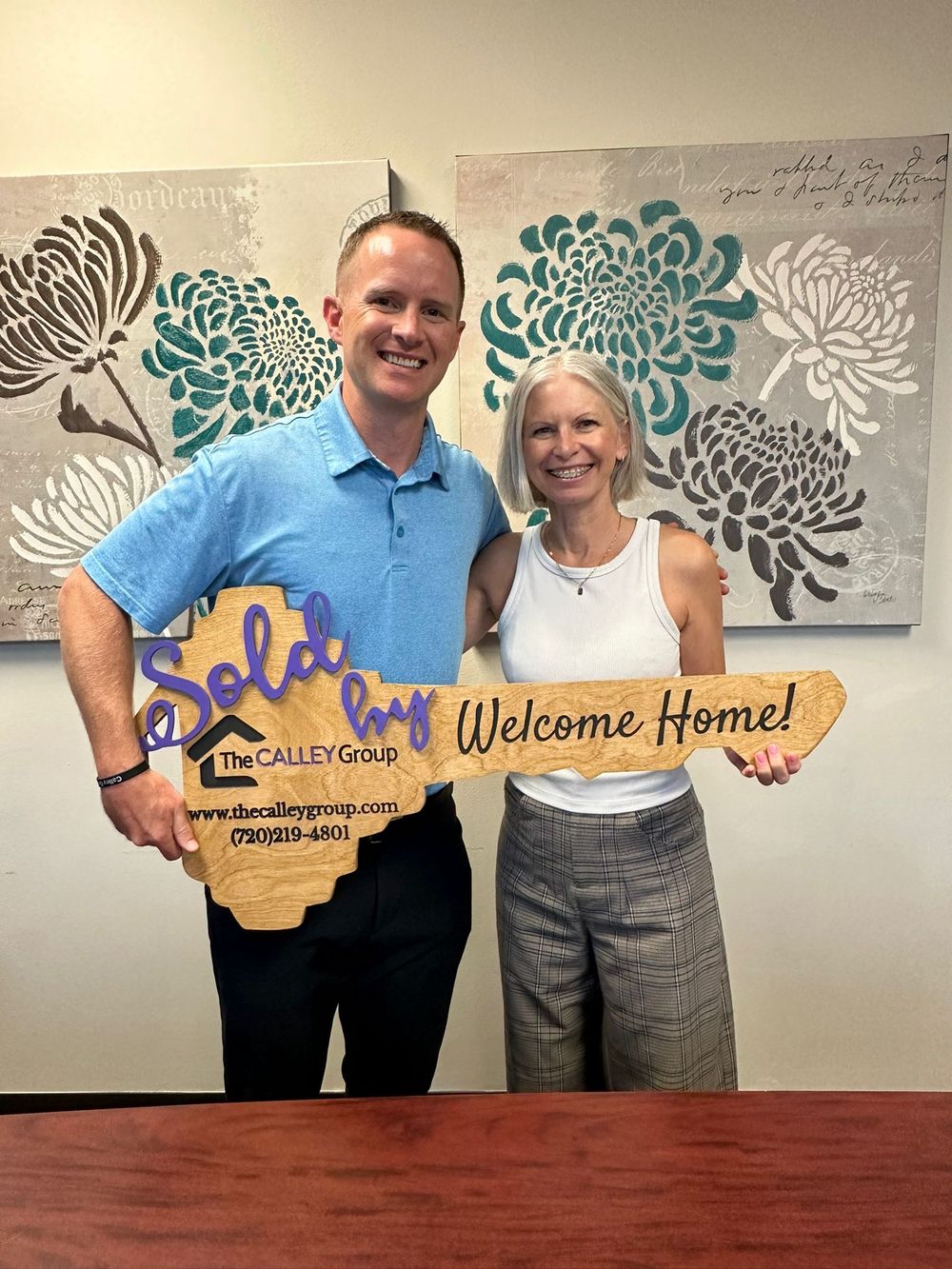 Steve Calley and a client holding the Welcome Home key sign.