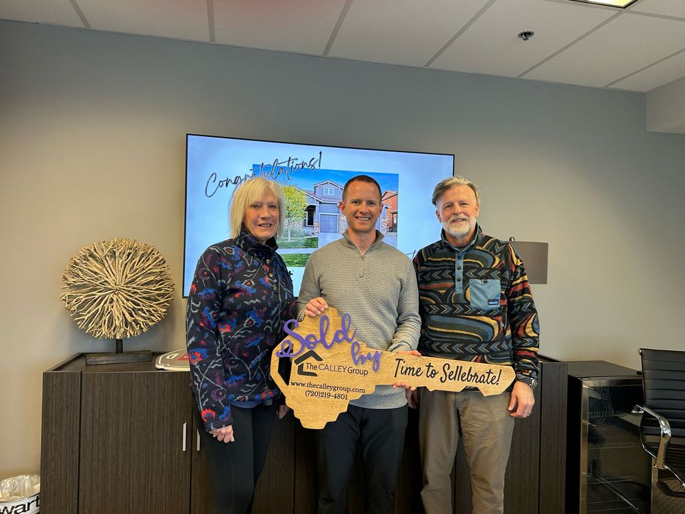 Steve Calley with two clients holding the Time to Sellebrate sign in front of a congratulations screen.