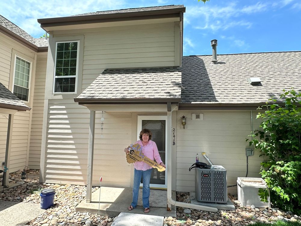 A homeowner holding the key-shaped closing sign outside her townhome.