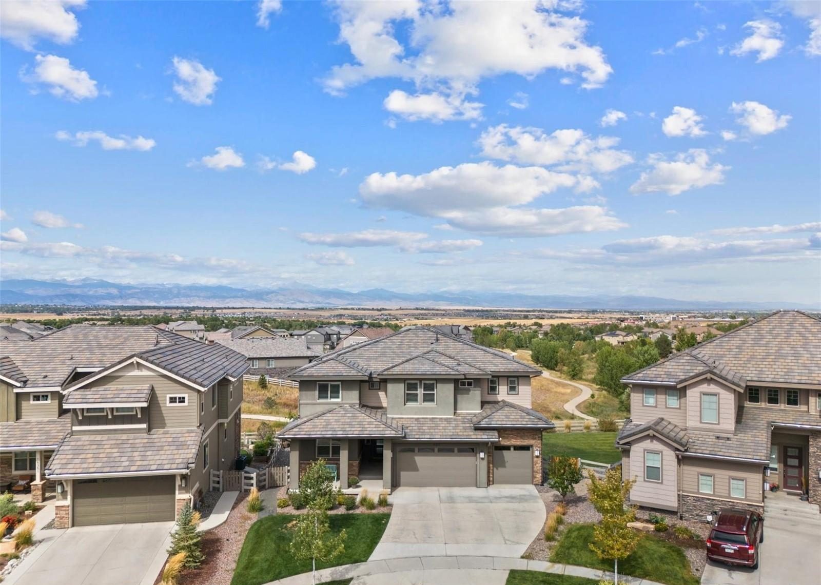 Aerial view over an Anthem Highlands cul-de-sac in Broomfield, with open space trails and the Front Range on the horizon.