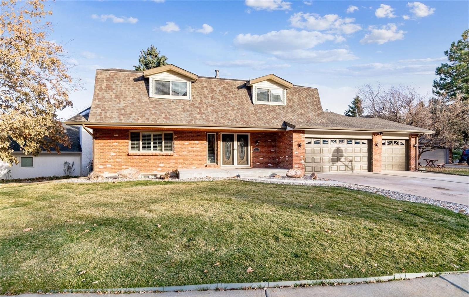 Two-story brick home with dormers and a three-car garage.