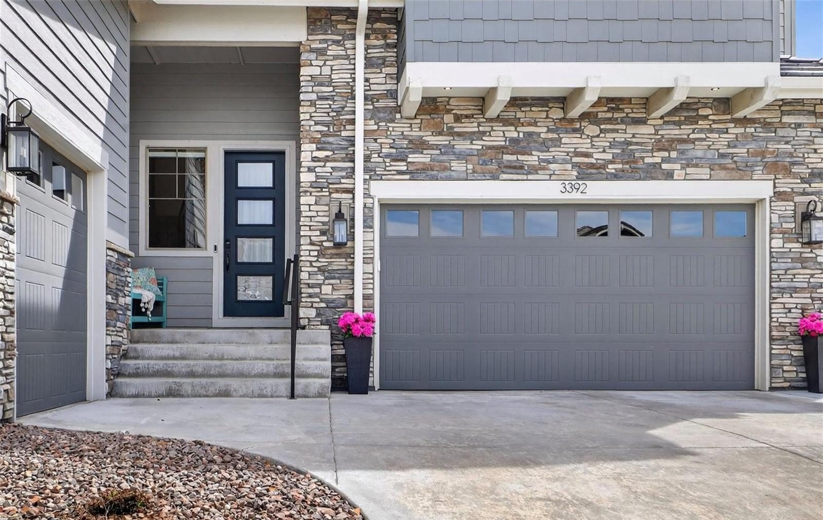 Modern entry with a stone wall and a dark garage door.