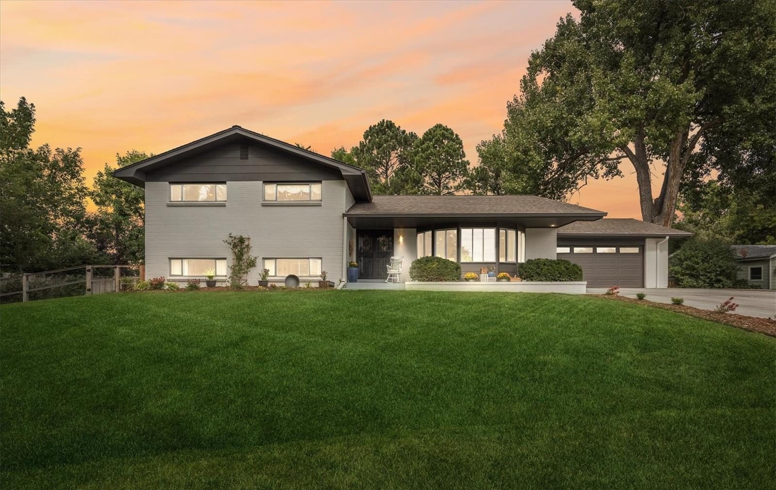 Mid-century home with a wide lawn at dusk.