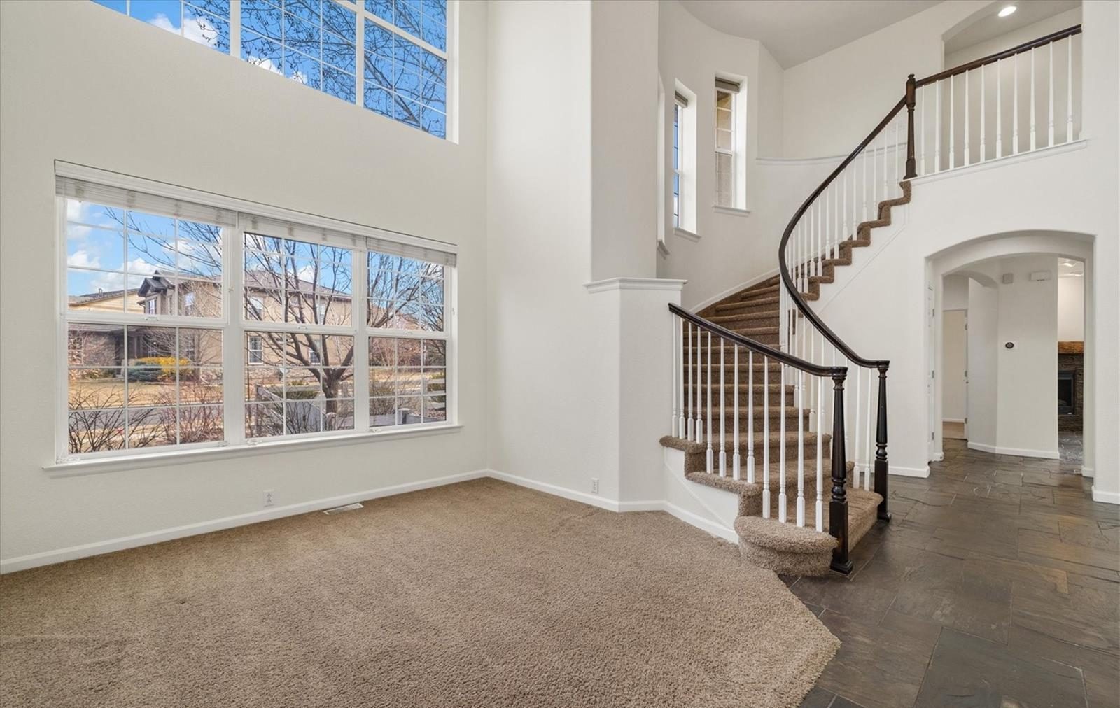 Two-story living room with a curved staircase and tall windows.