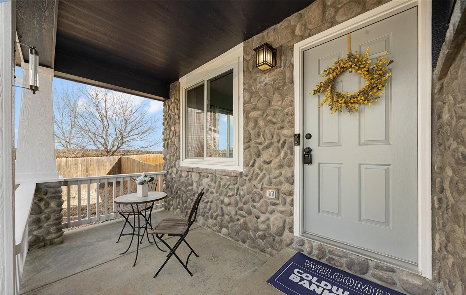 Covered front porch with a wreath and bistro chairs in Thornton.