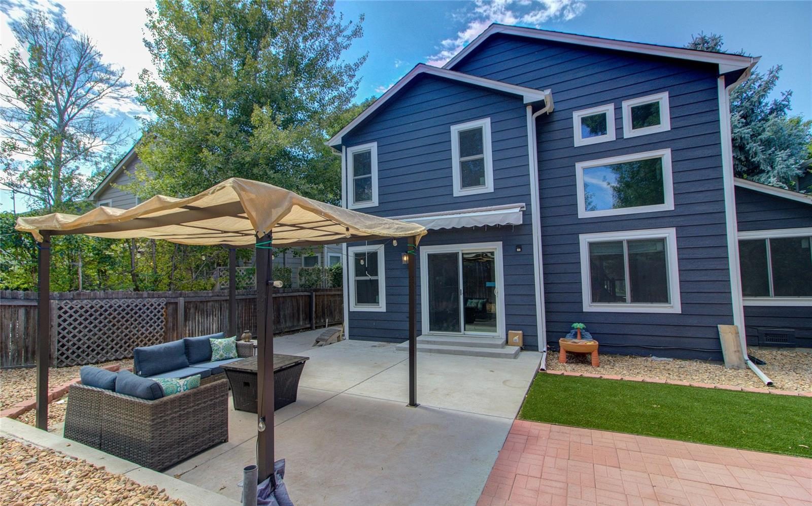 Back patio with a pergola behind a blue two-story home in Thornton.