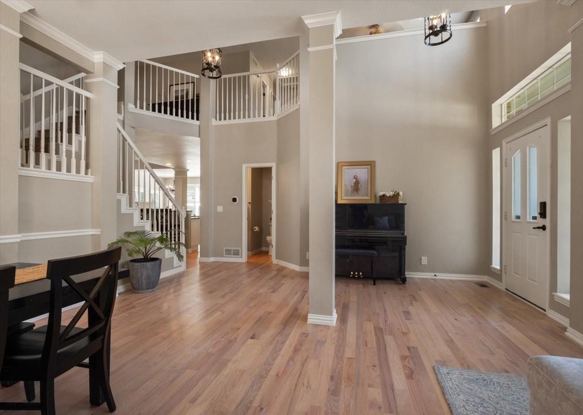 Two-story foyer with a piano and wood floors.