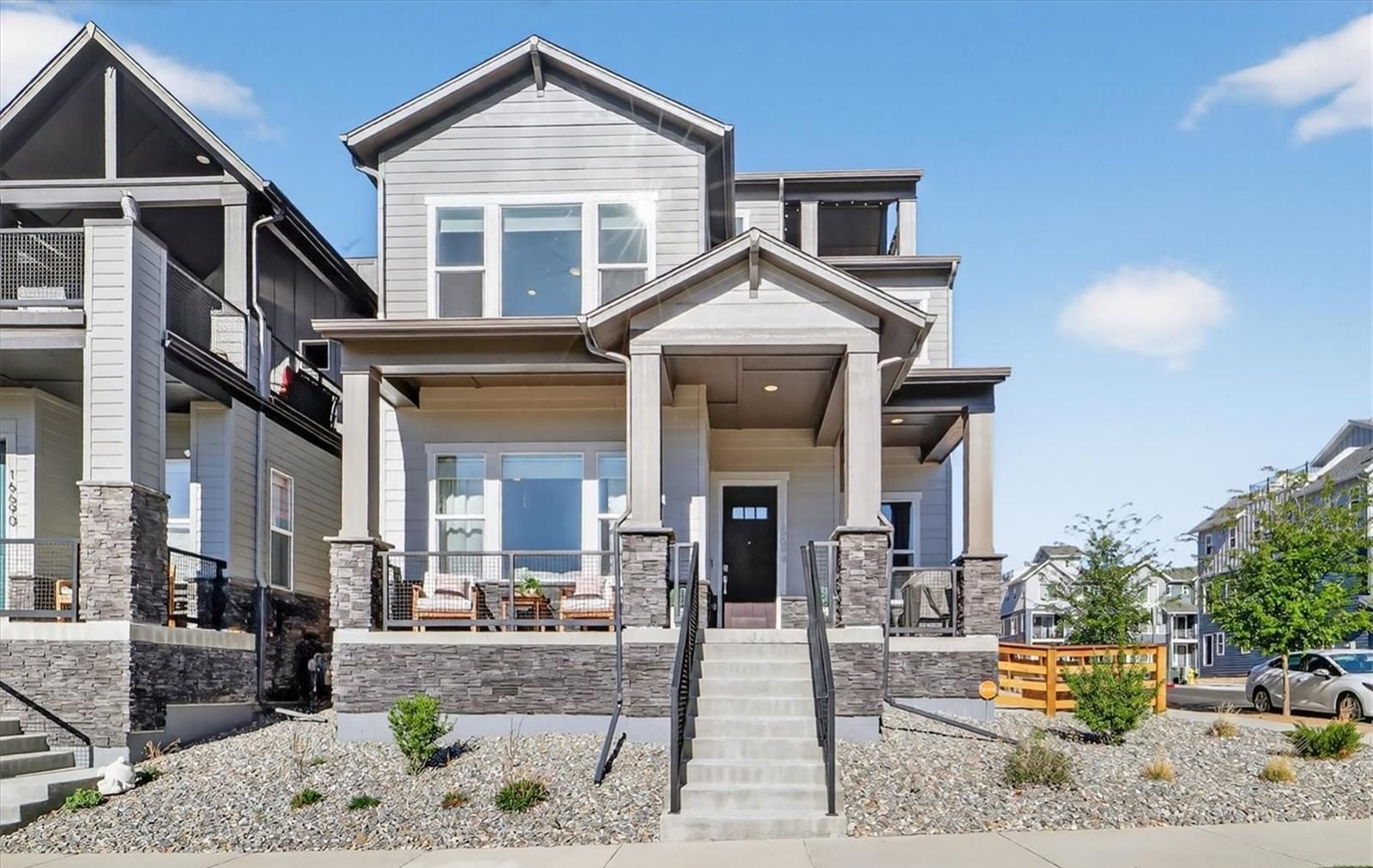 Front steps and covered porch of a three-story home in Broomfield on a sunny day.