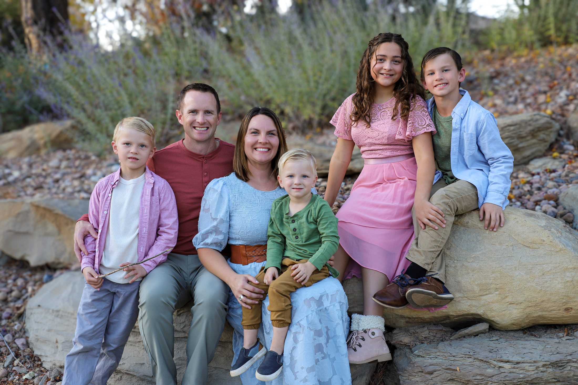Steve Calley with his wife and their four children, sitting together on a boulder outdoors in the fall.