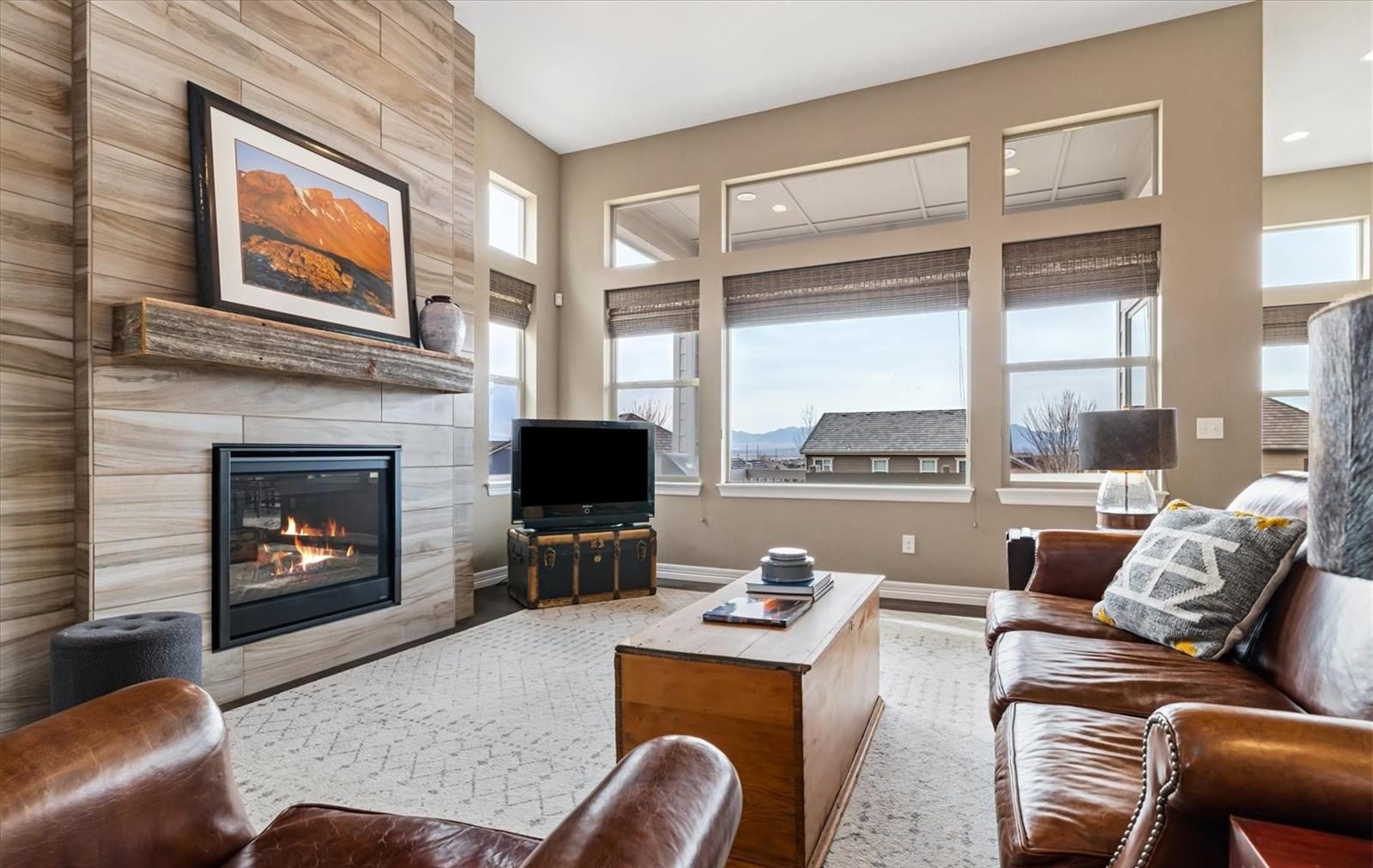Family room with a tiled fireplace wall, a wood mantel and tall windows in a Broomfield home.