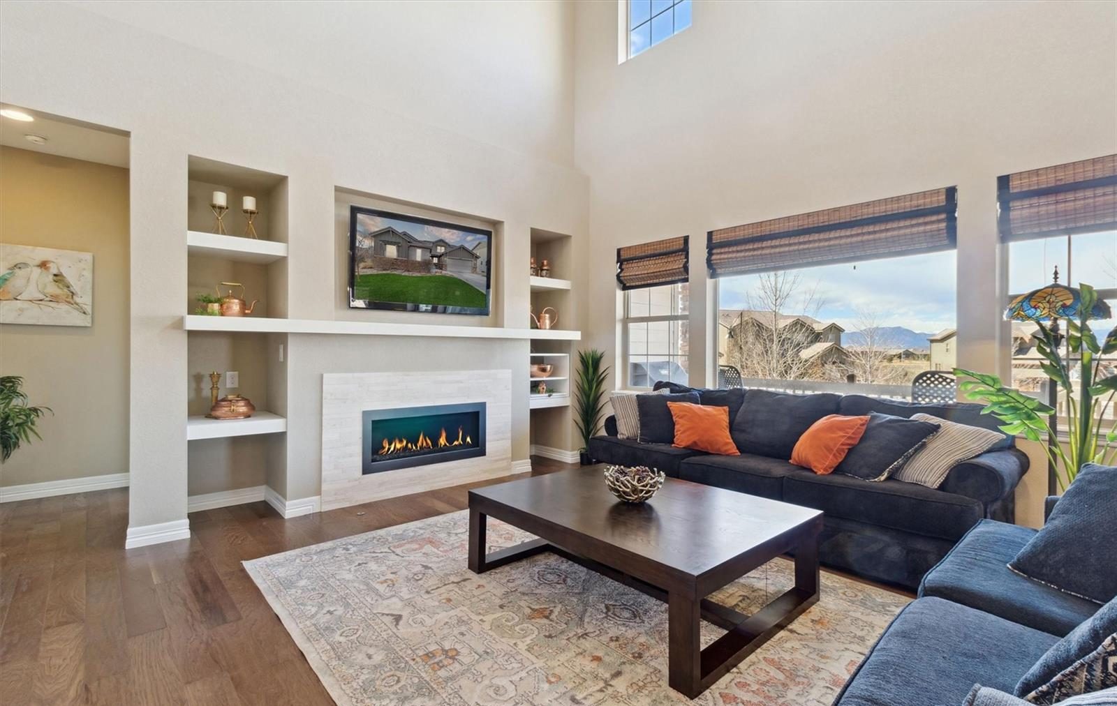 Great room with tall windows, built-in shelves and a view of the Front Range in an Anthem Highlands home.