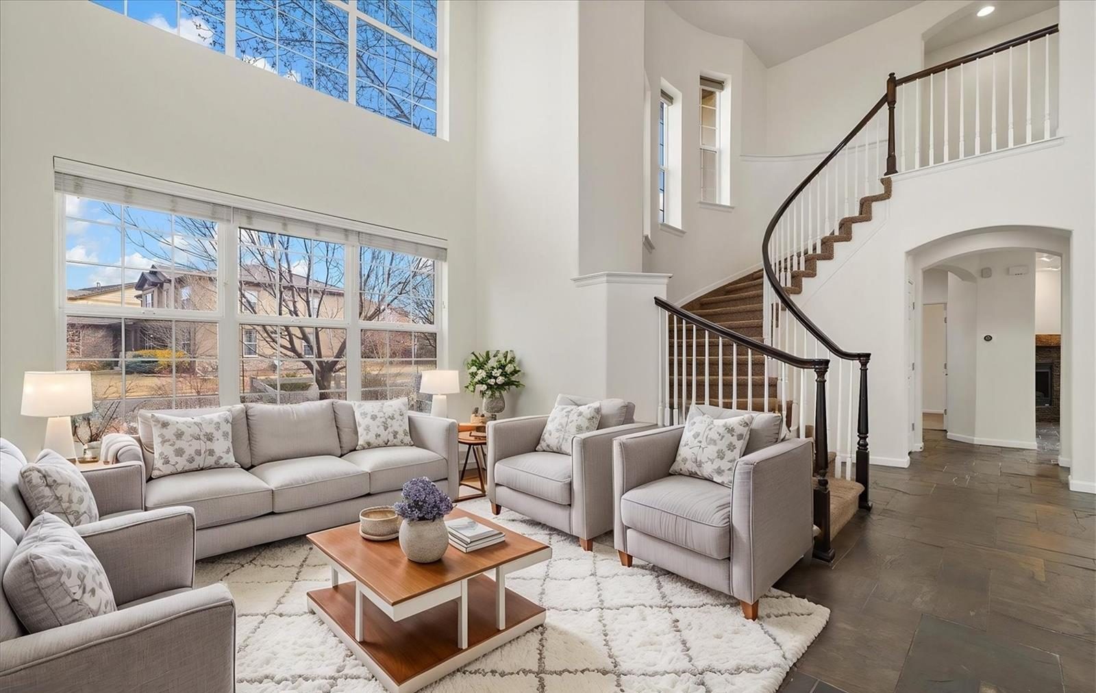 Two-story living room with a curved staircase and tall windows.