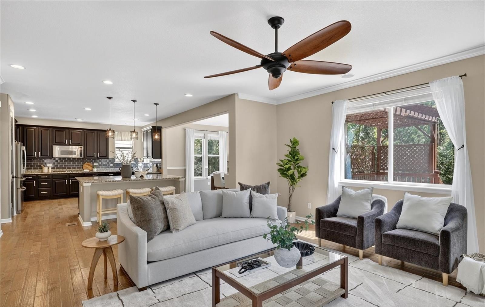 Staged living room with a gray sofa, armchairs and a ceiling fan.