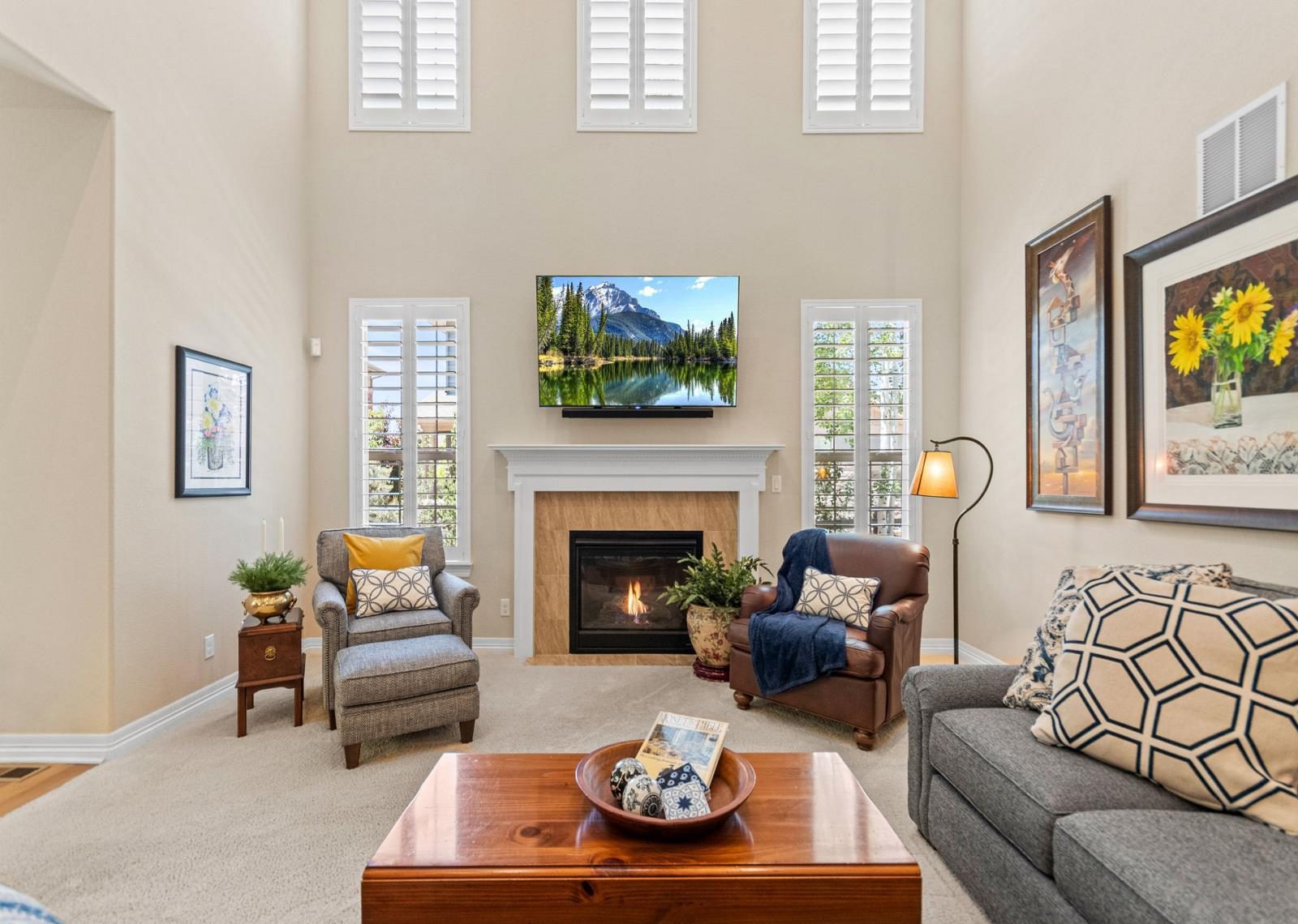 Two-story living room with a fireplace and tall windows in a Broomfield home.