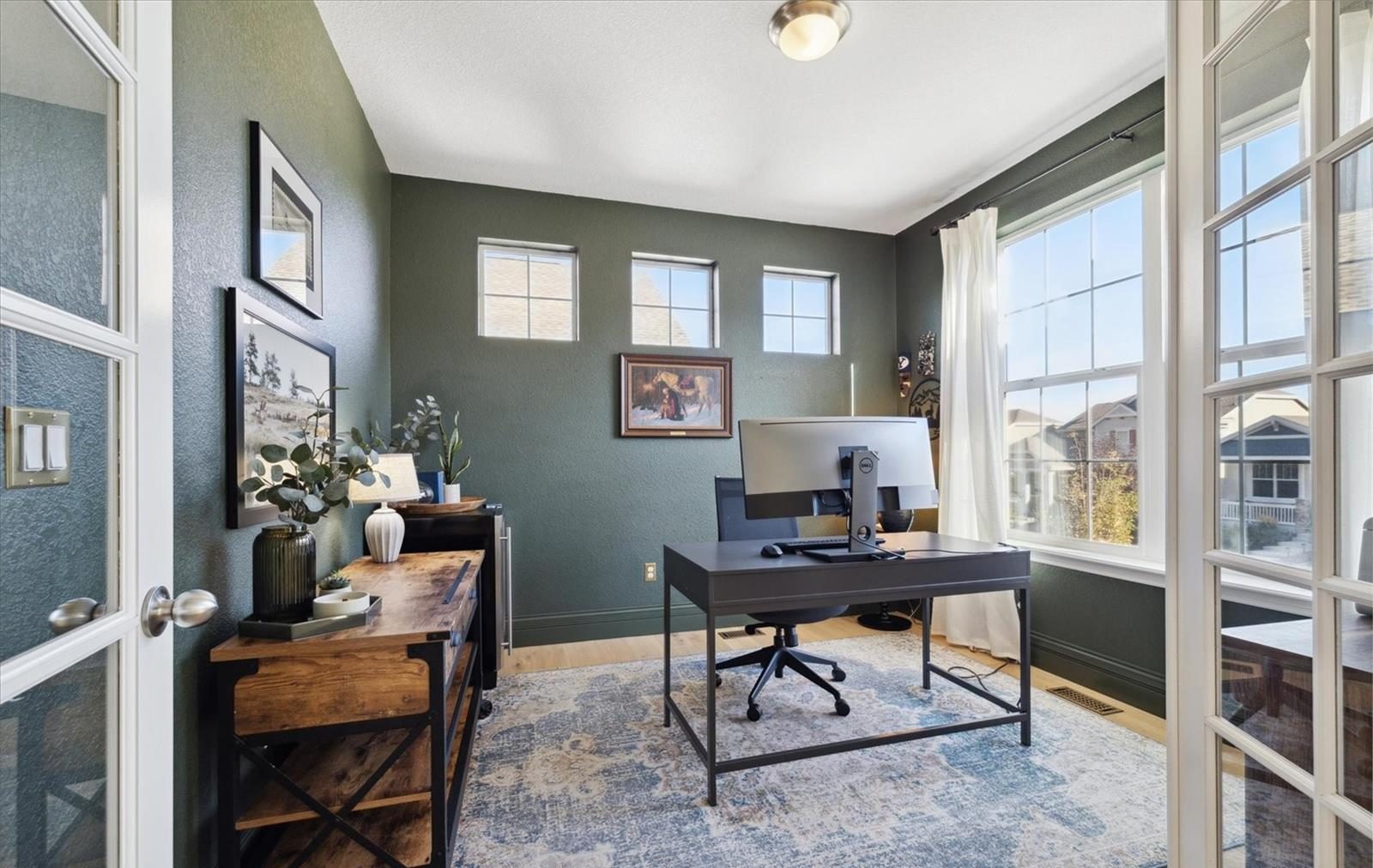 Home office with a wood desk and French doors in an Arvada home.