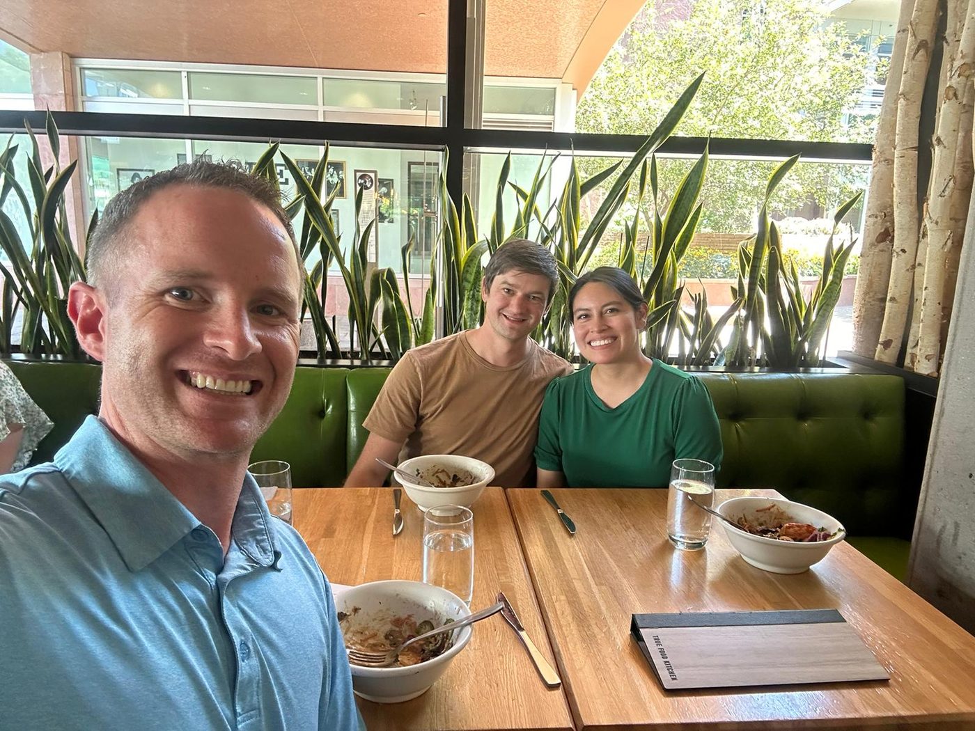 Steve Calley taking a selfie with two clients across a restaurant table.