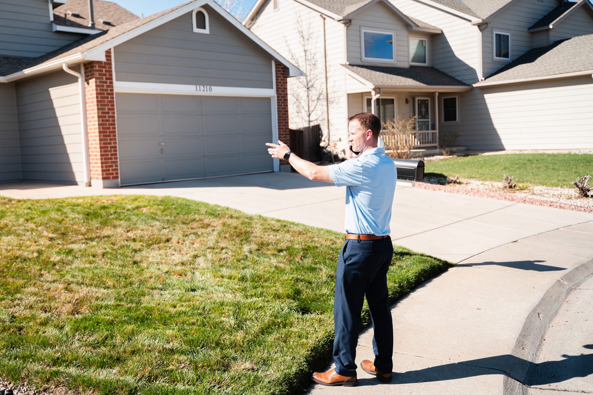 Steve Calley on a driveway pointing out features of a two-story home.