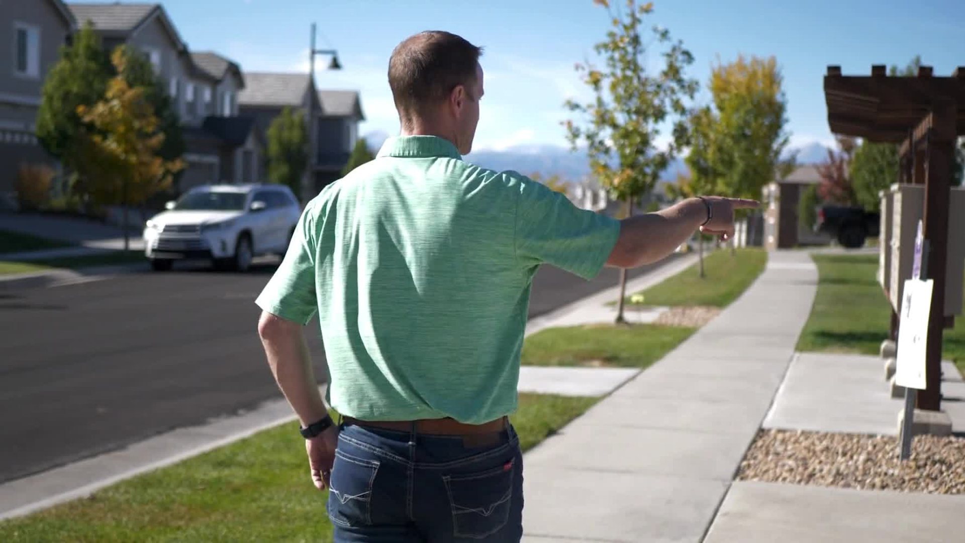 Steve Calley on a Broomfield sidewalk, pointing down the street.
